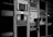 A collection of vintage electronic equipment is mounted in tall racks, featuring a variety of dials, knobs, and screens. Each unit appears to be a specialized piece of technology, possibly related to broadcasting or audio engineering. Cables are visibly hanging down the side of one rack.