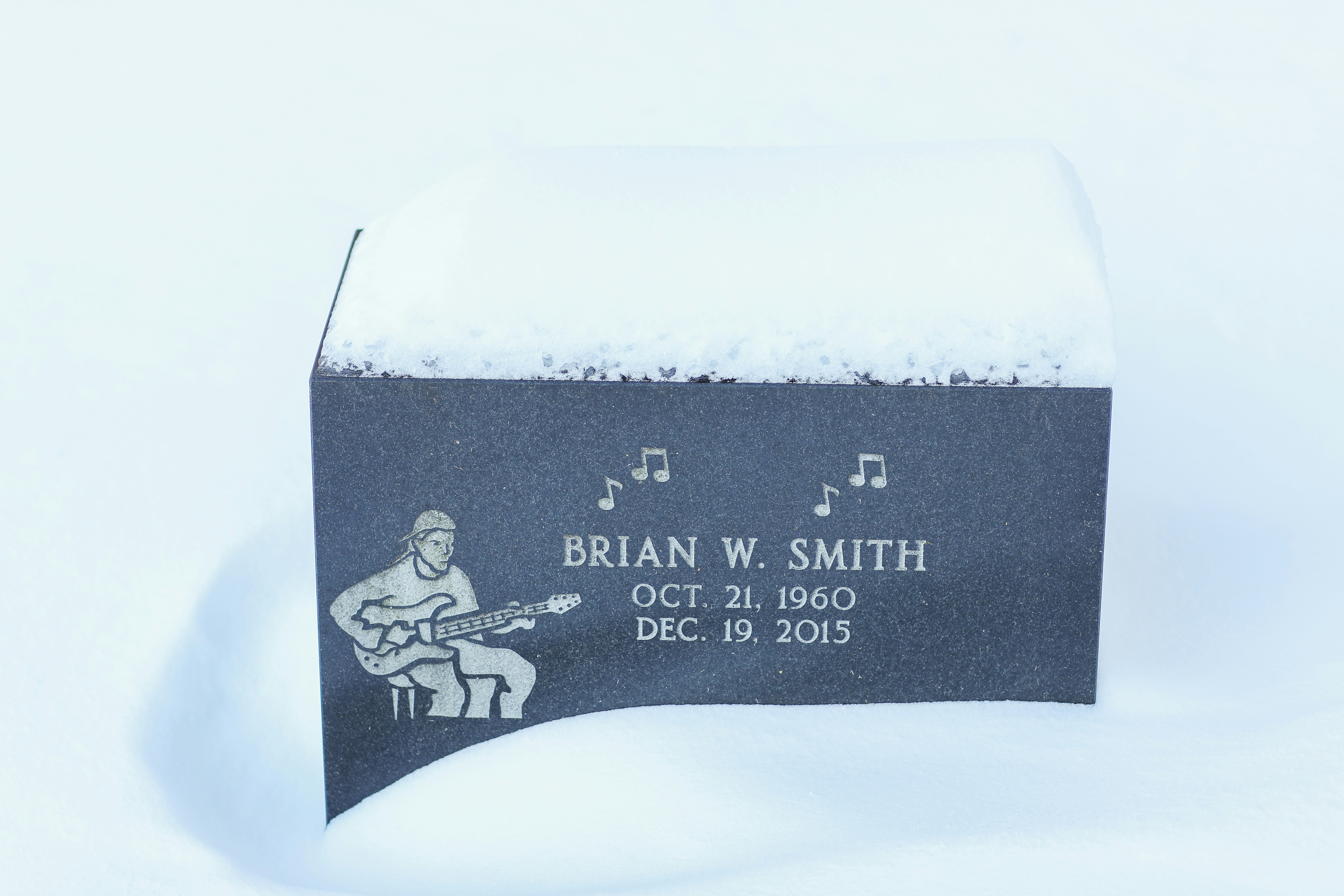 a memorial plaque with a guitar player on it in the snow