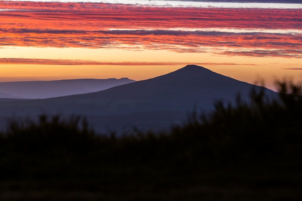 uma vista de uma montanha ao pôr do sol à distância