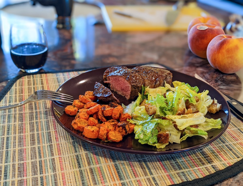 a plate of food with meat, lettuce and carrots