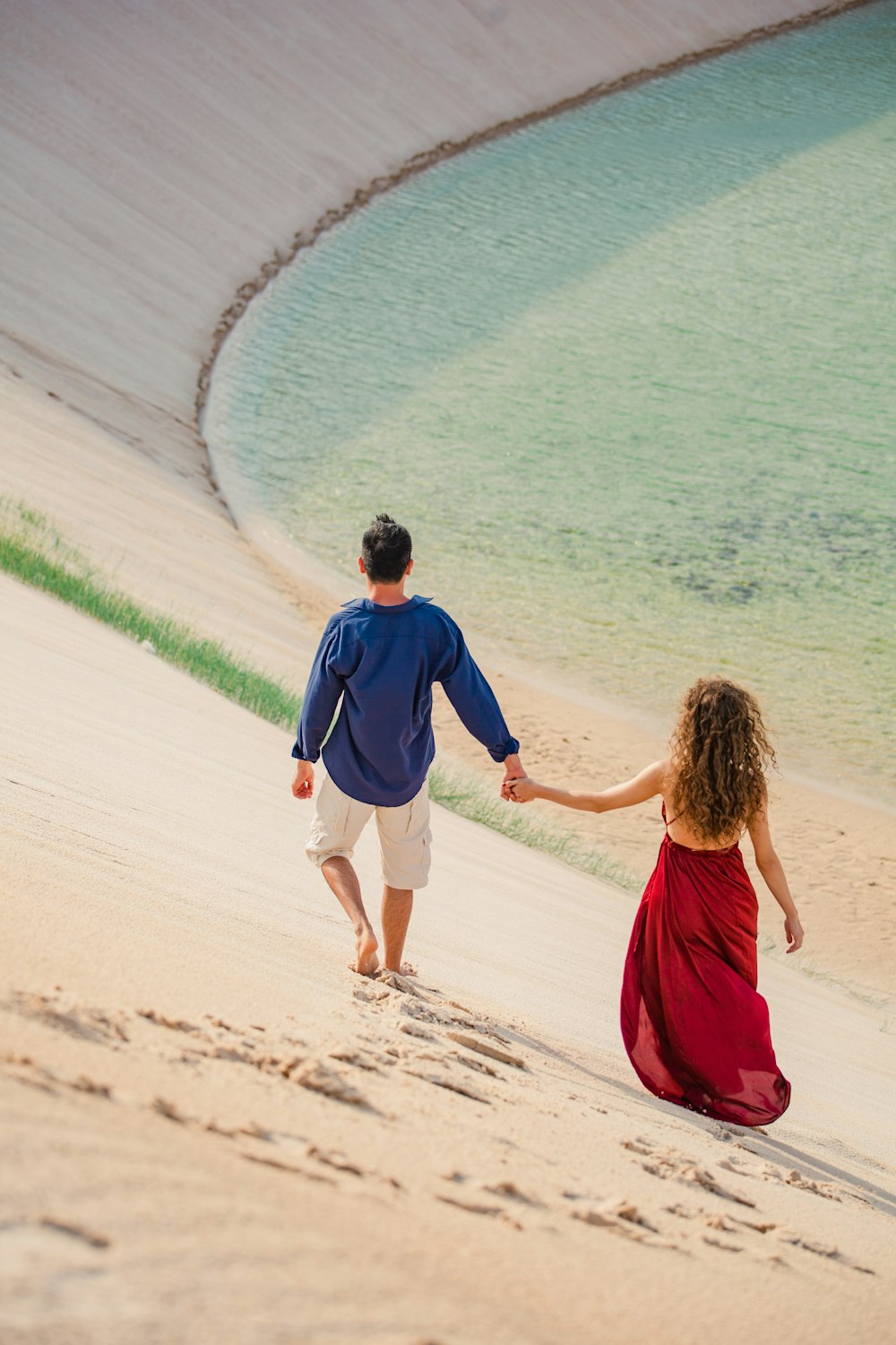 a man and a woman walking on a beach holding hands