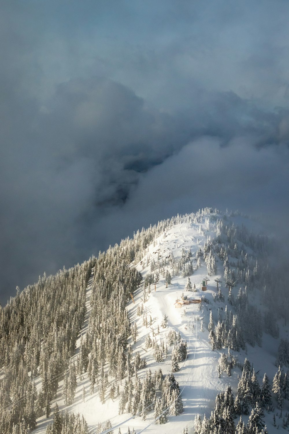 a mountain covered in snow and trees under a cloudy sky