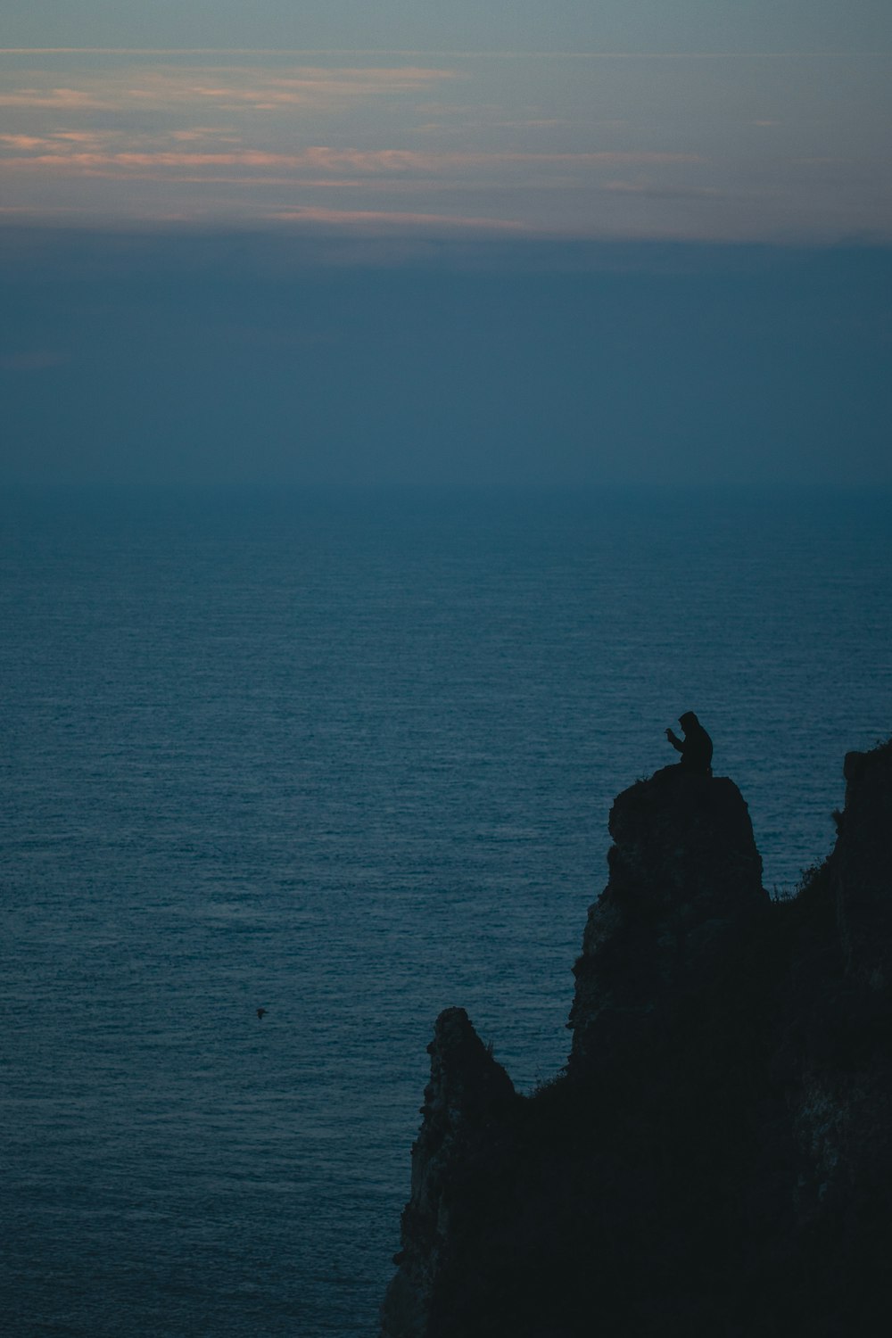 a person sitting on a cliff overlooking the ocean