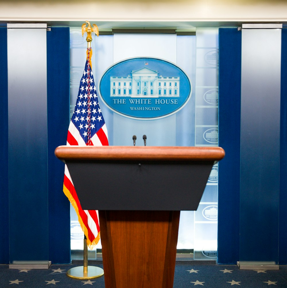 a podium with an american flag and the white house