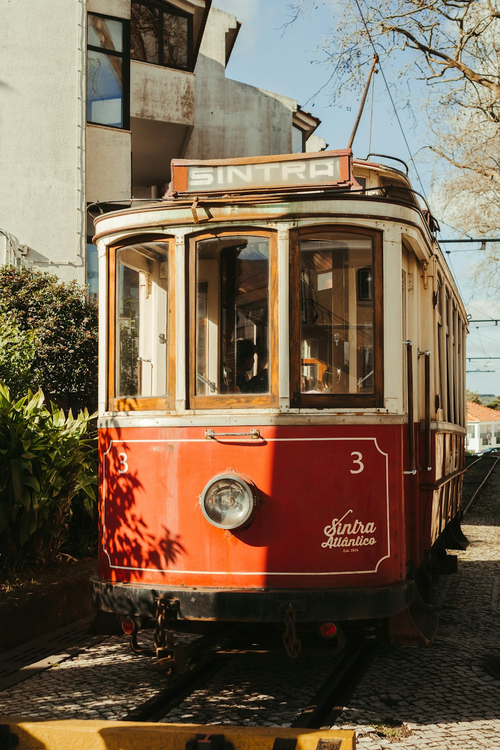 a red and white trolley car traveling down a street