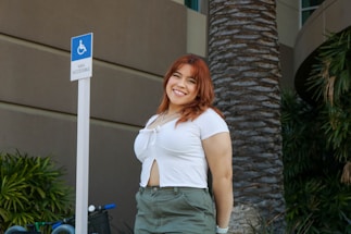 A friendly driver assisting a passenger into a wheelchair-accessible van outside a sunny West Palm Beach clinic.