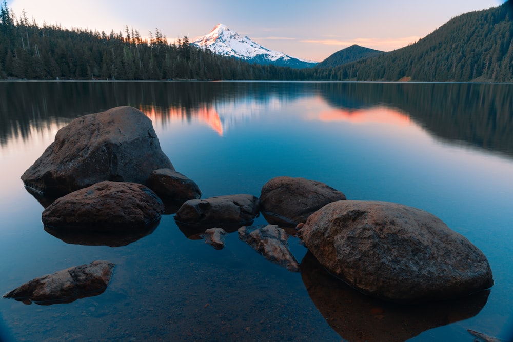 a lake with some rocks in it and a mountain in the background