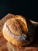 A rustic loaf of bread with a golden crust on a wooden table.