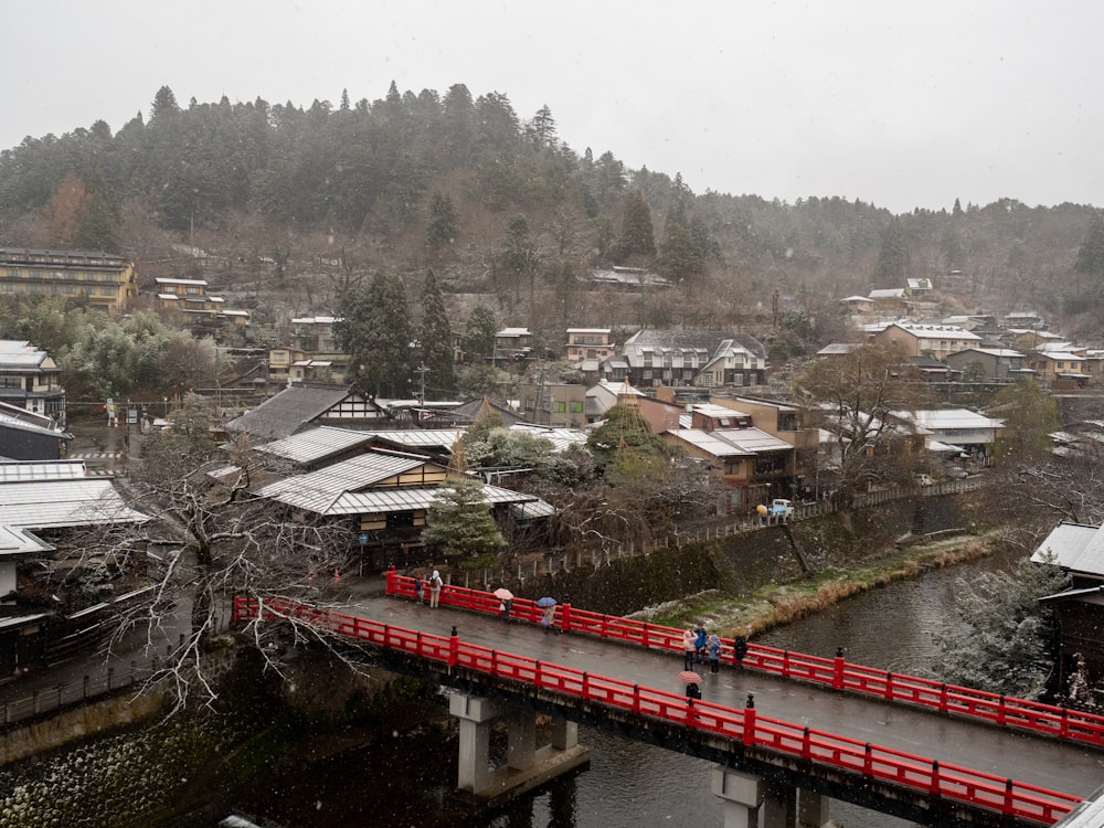 a red bridge over a river in a small town