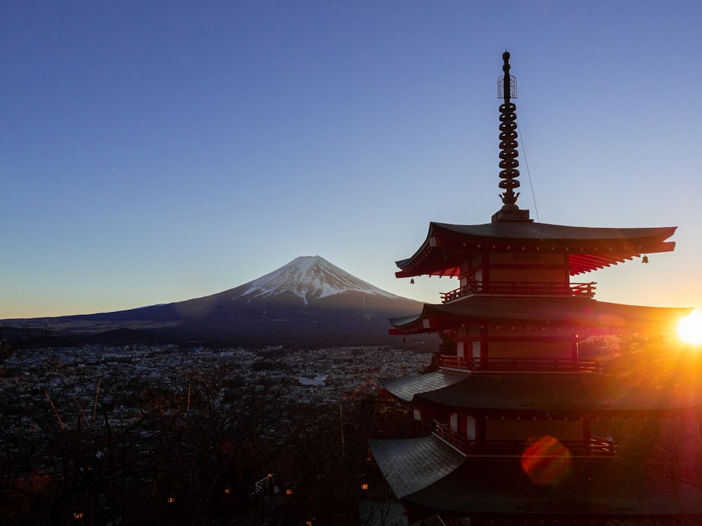 the sun is setting behind a pagoda with a mountain in the background