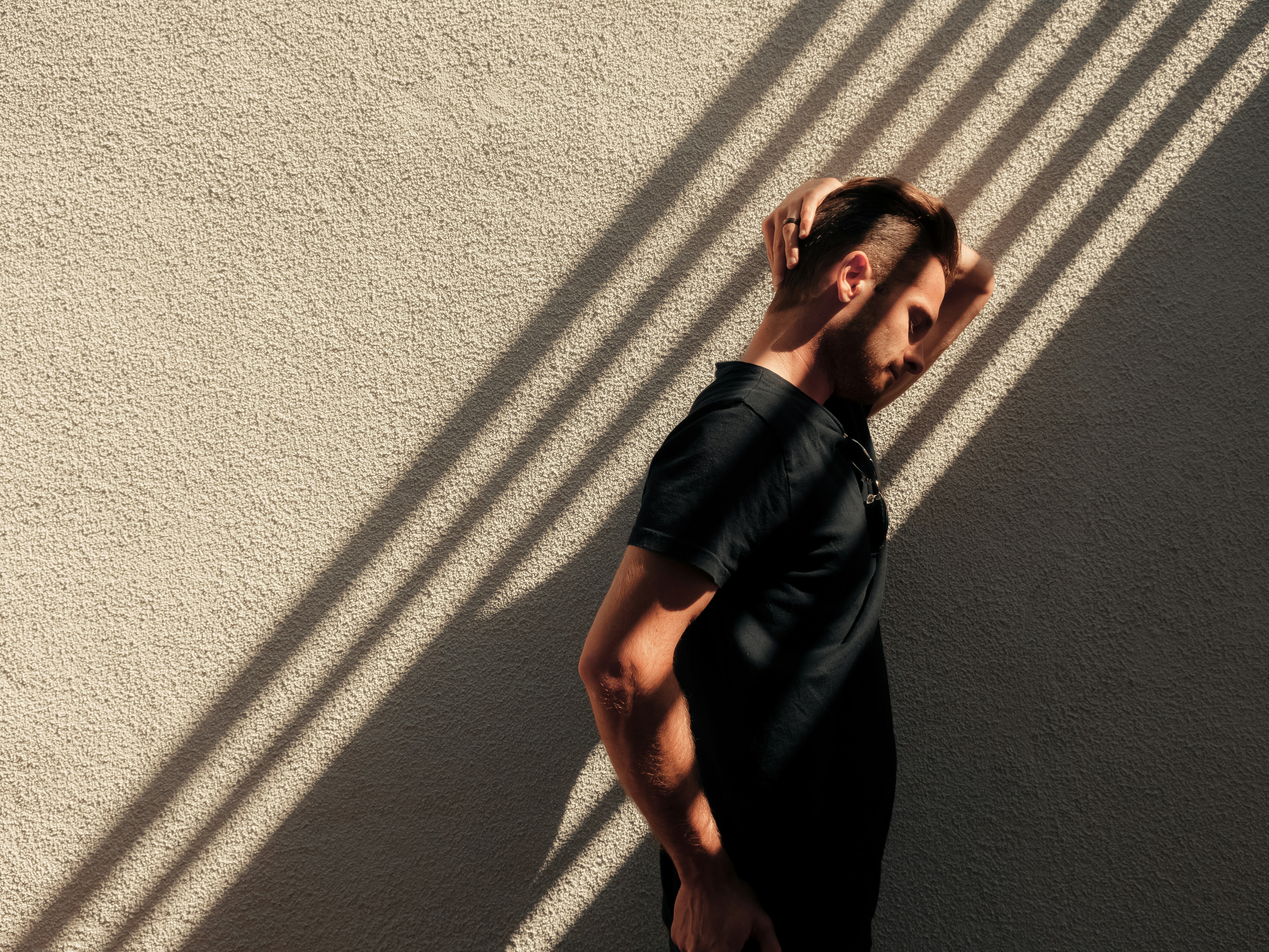 a man standing in front of a wall with his hand on his head