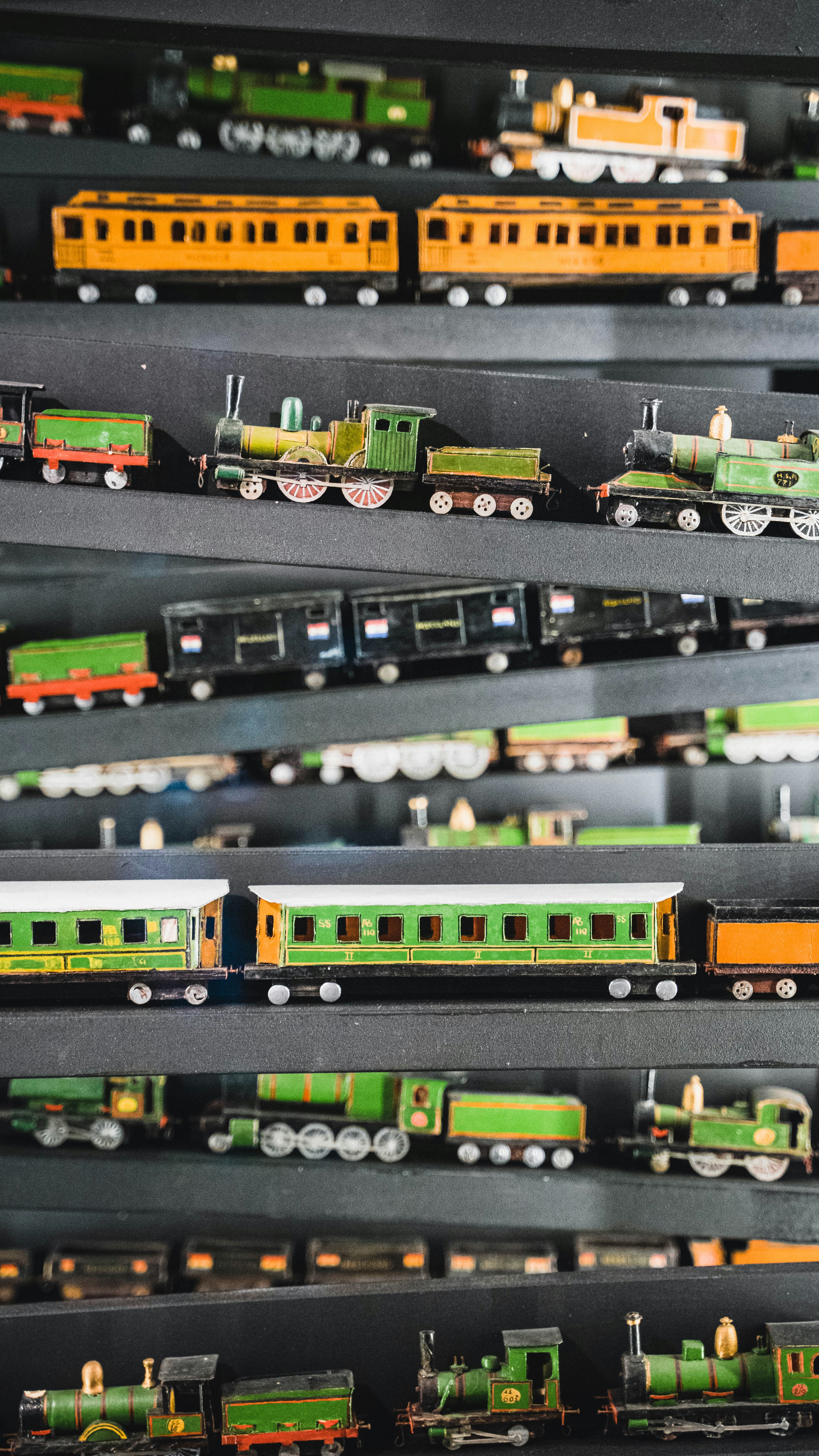 Miniature di trenini d'epoca disposte in file su scaffali scuri.