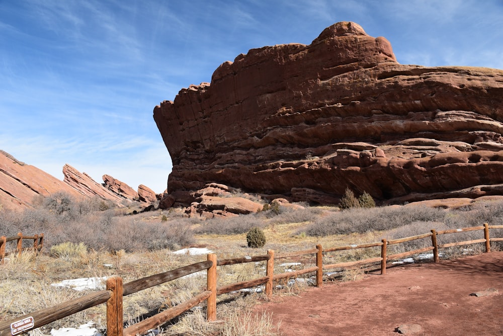 a wooden fence in front of a large rock formation