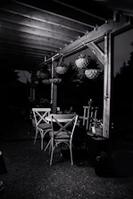Elegant outdoor dining set arranged under a pergola with soft evening lighting.