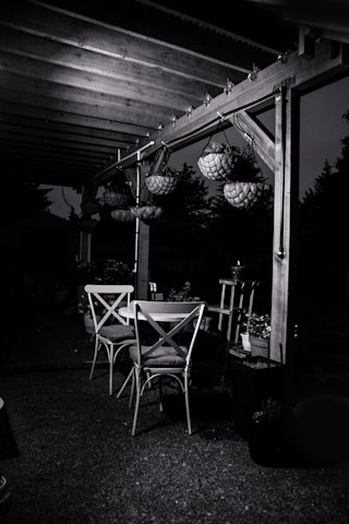 An elegant outdoor dining set placed on a stone patio under a shaded gazebo.
