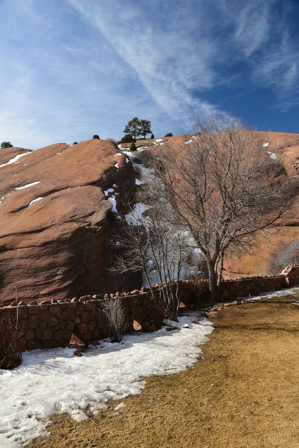 a snow covered field next to a large rock formation