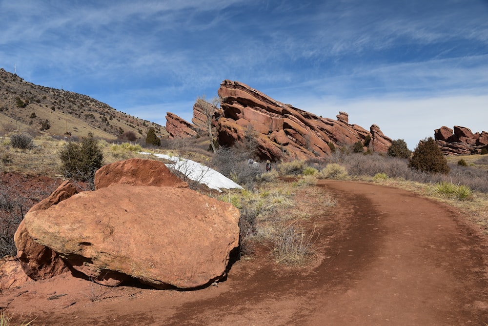 a dirt road with a large rock in the middle of it