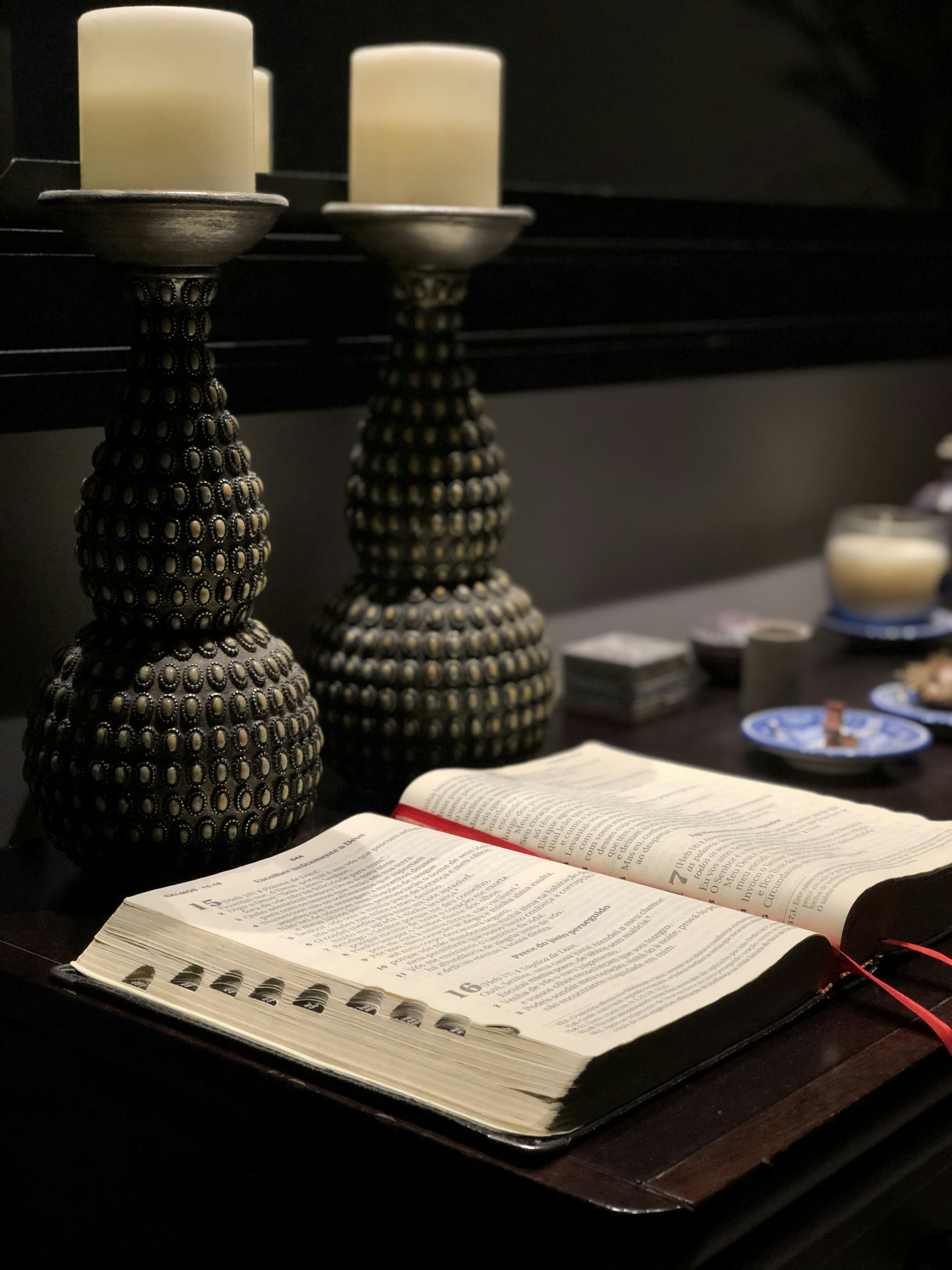 an open book sitting on top of a table next to two candles