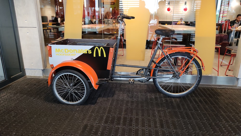 an orange and black bike with a mcdonald's cart on the back