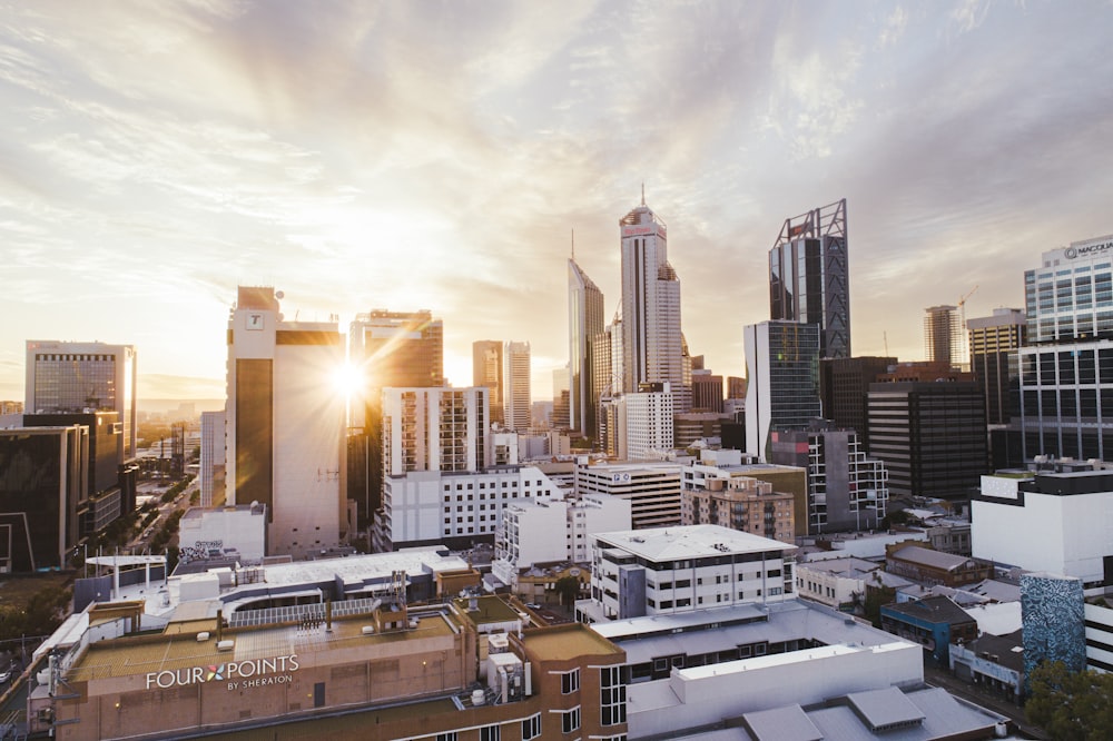 the sun is setting over a city with tall buildings