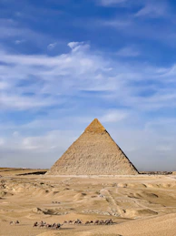 a group of people riding camels in front of a pyramid