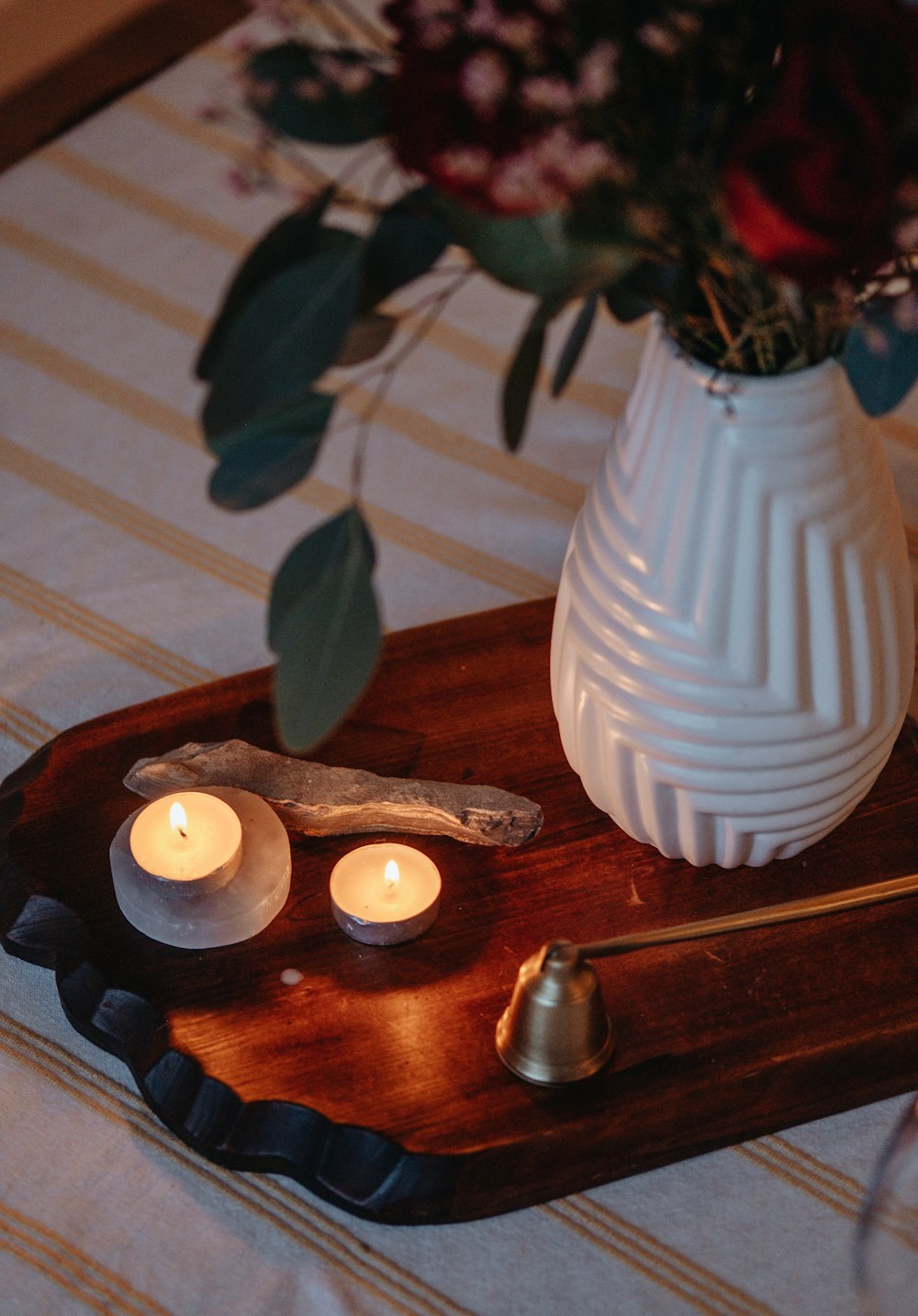 a tray with candles and a vase with flowers