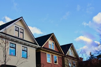 A vibrant display of different roof styles and colors on charming houses under a clear blue sky.