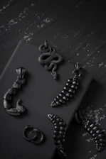 A dark, moody grid of gothic jewelry pieces with subtle silver highlights and crimson accents.