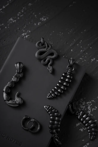 Minimalist gold and black unisex jewellery pieces displayed on a white marble surface.
