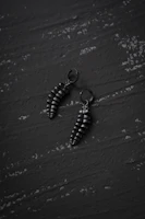 Minimalist black and silver earrings displayed on a sleek dark surface highlighting their modern design.