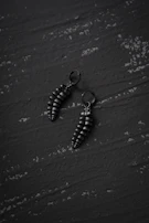 A pair of bold statement earrings with clean lines showcased on a matte black pedestal.