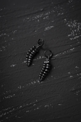 Sophisticated earrings featuring geometric shapes against a charcoal surface.