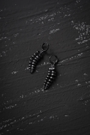 Minimalist black and silver earrings displayed on a sleek dark surface highlighting their modern design.