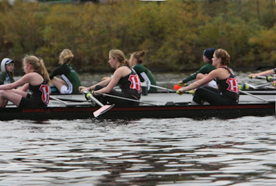 Coaches and players sharing a focused moment during intense training on calm waters at dawn.
