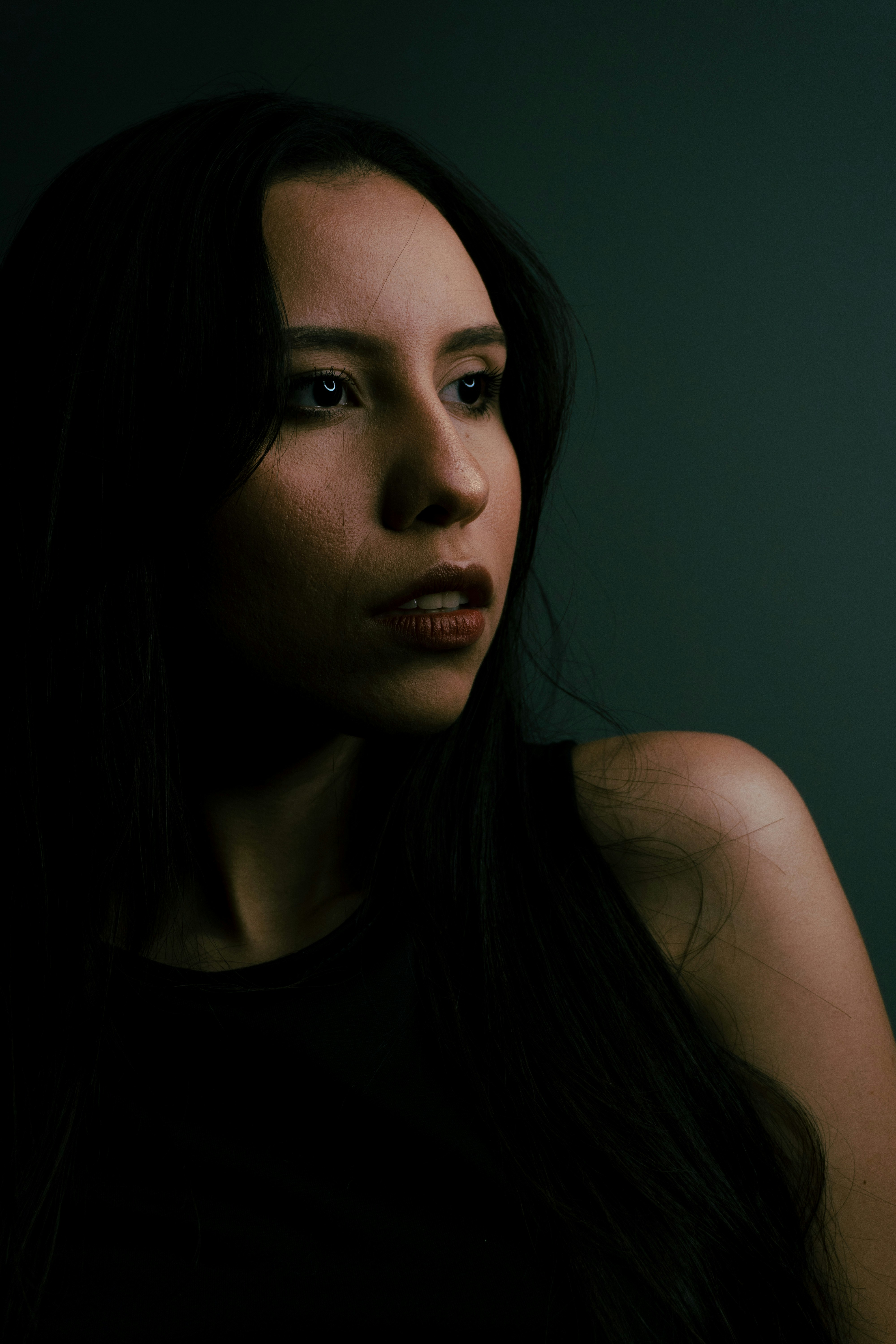 a woman with long black hair and a dark background