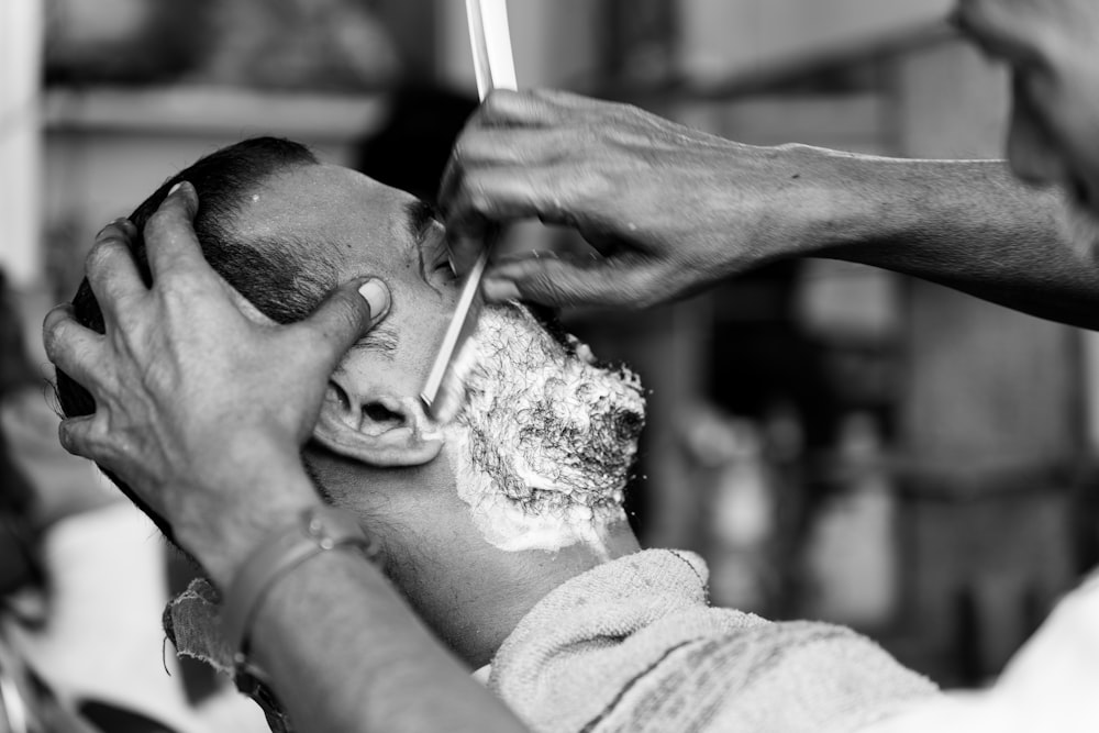 a black and white photo of a man getting his hair cut