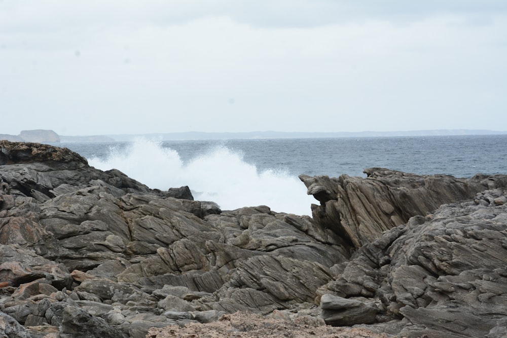 a wave crashing on rocks near the ocean