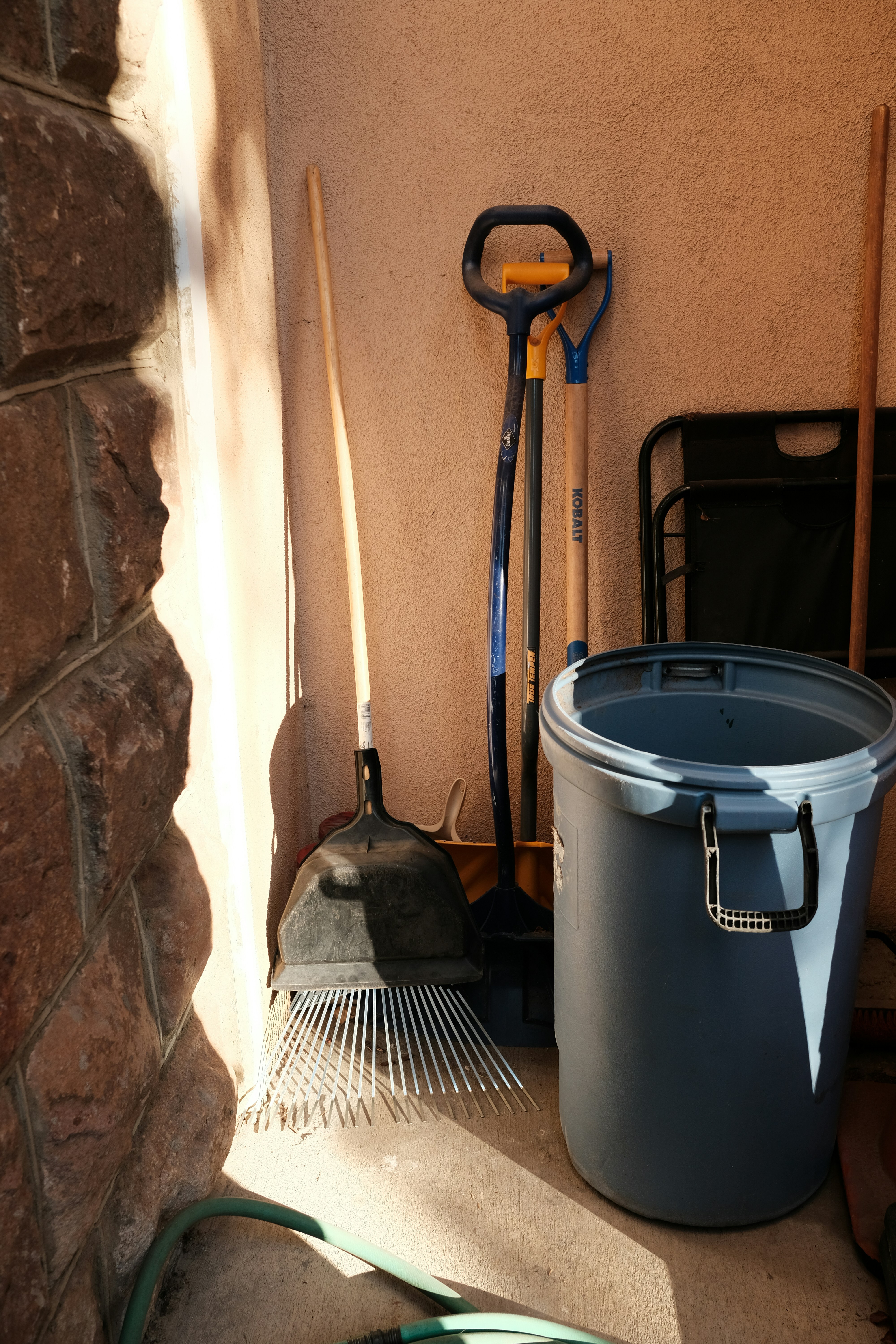 a bucket and shovels sitting next to a brick wall