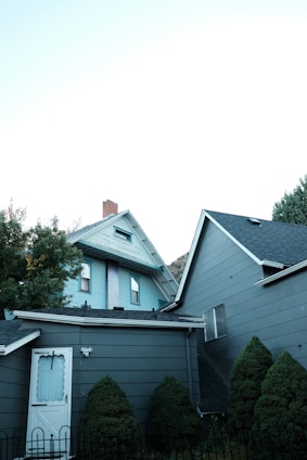 a gray house with a white door and a black fence