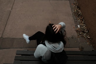 a person sitting on a bench on a sidewalk