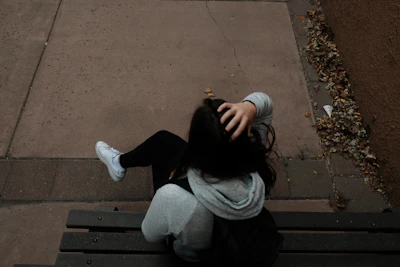 a person sitting on a bench on a sidewalk