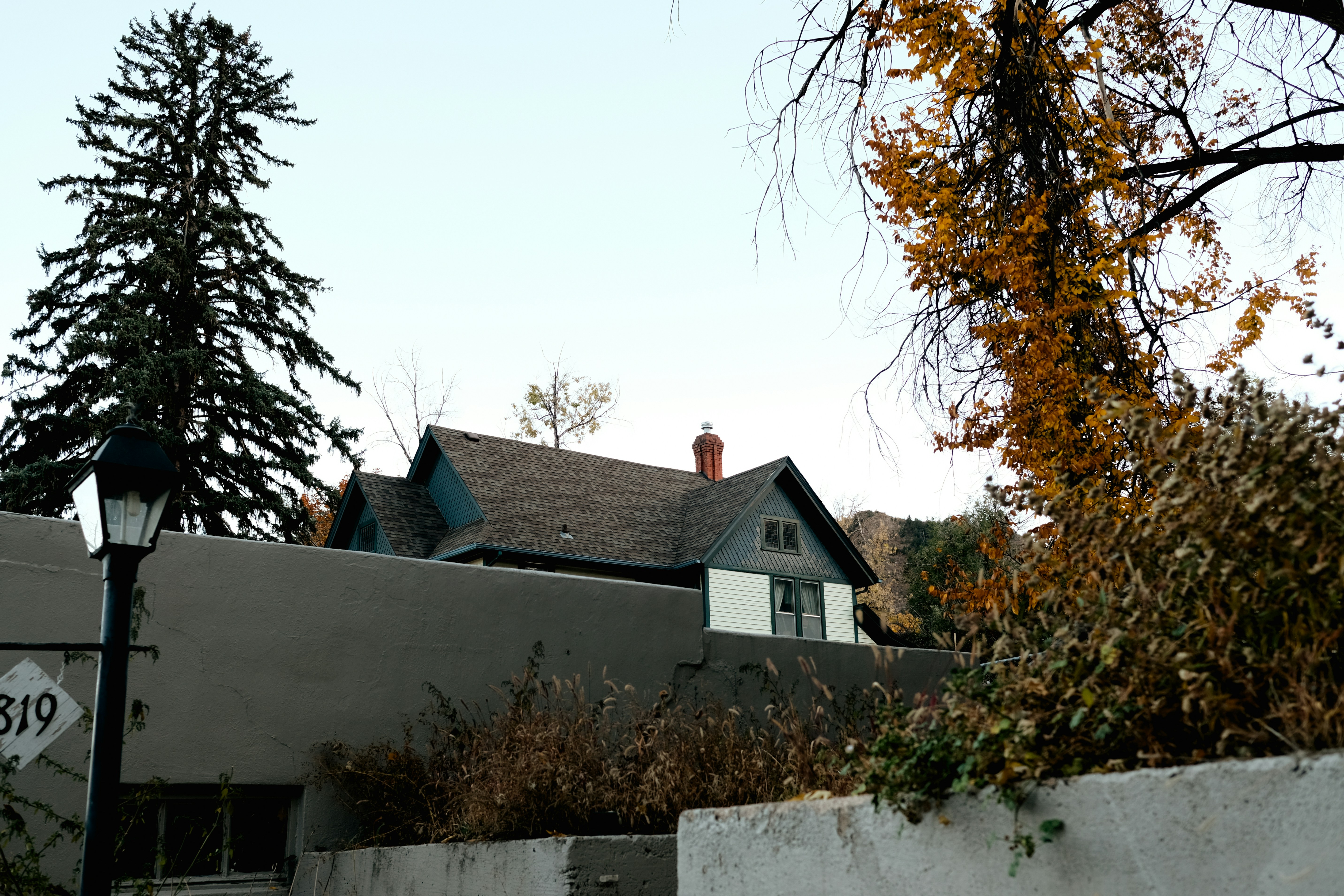A modern suburban house viewed from the street, showcasing a pristine, newly installed dark shingle roof against a clear blue sky.