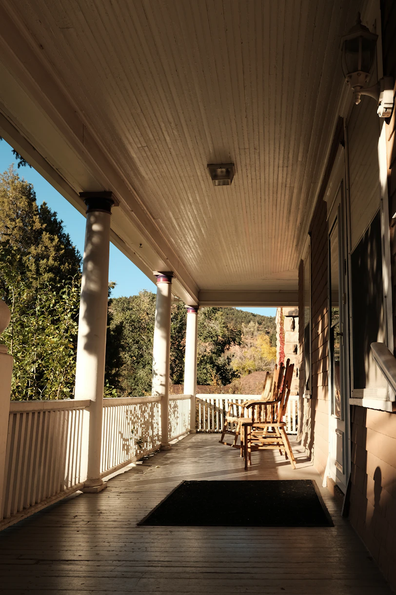 a porch with rocking chairs and a rug on it