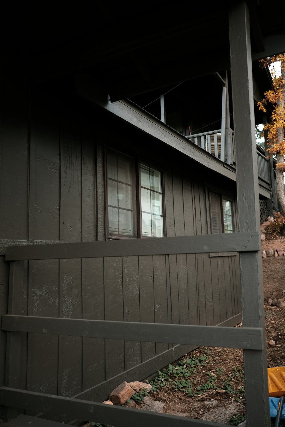 a brown house with a black fence and a tree