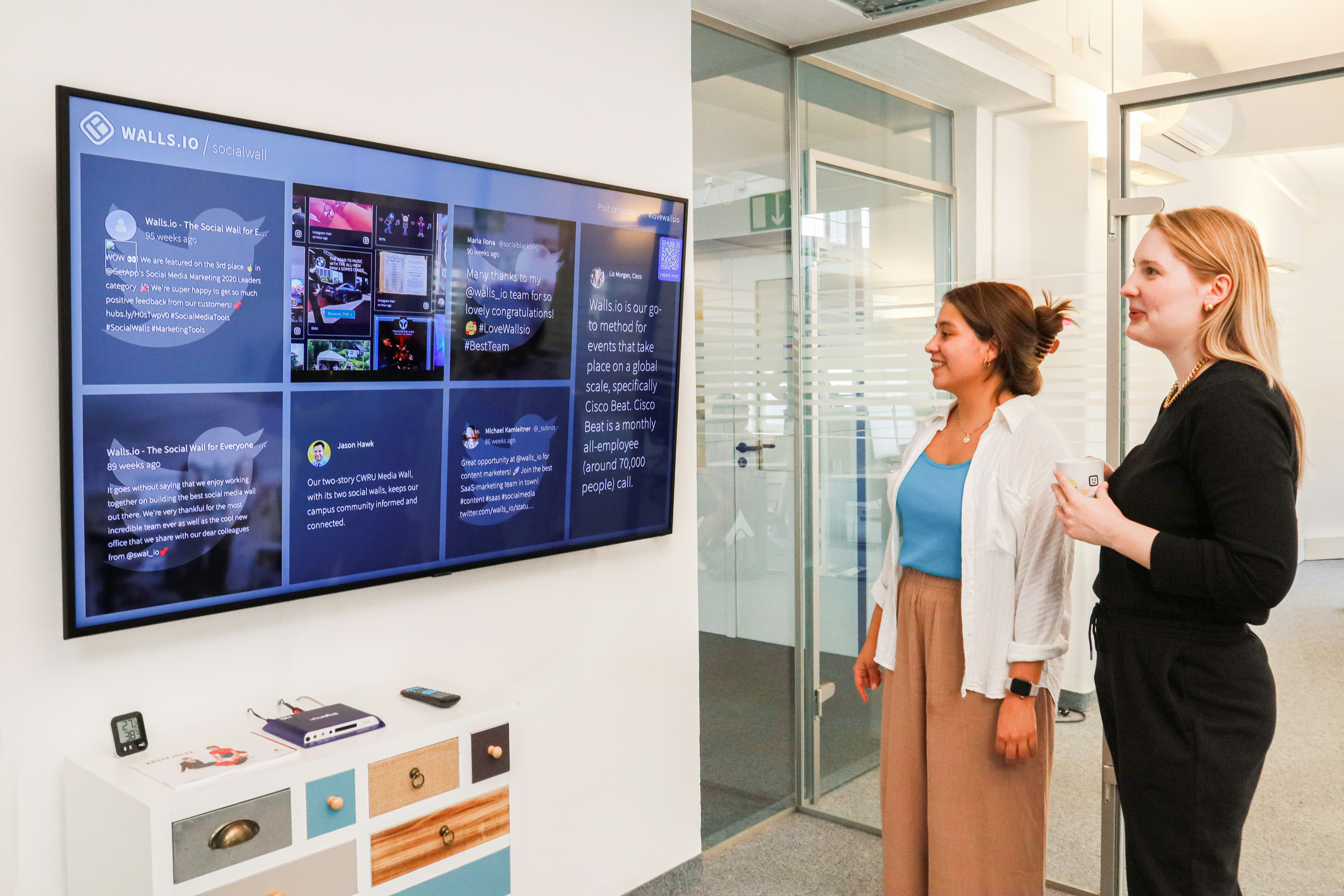 two women standing in front of a large screen