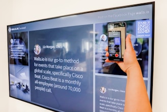 a person holding a cell phone in front of a large screen