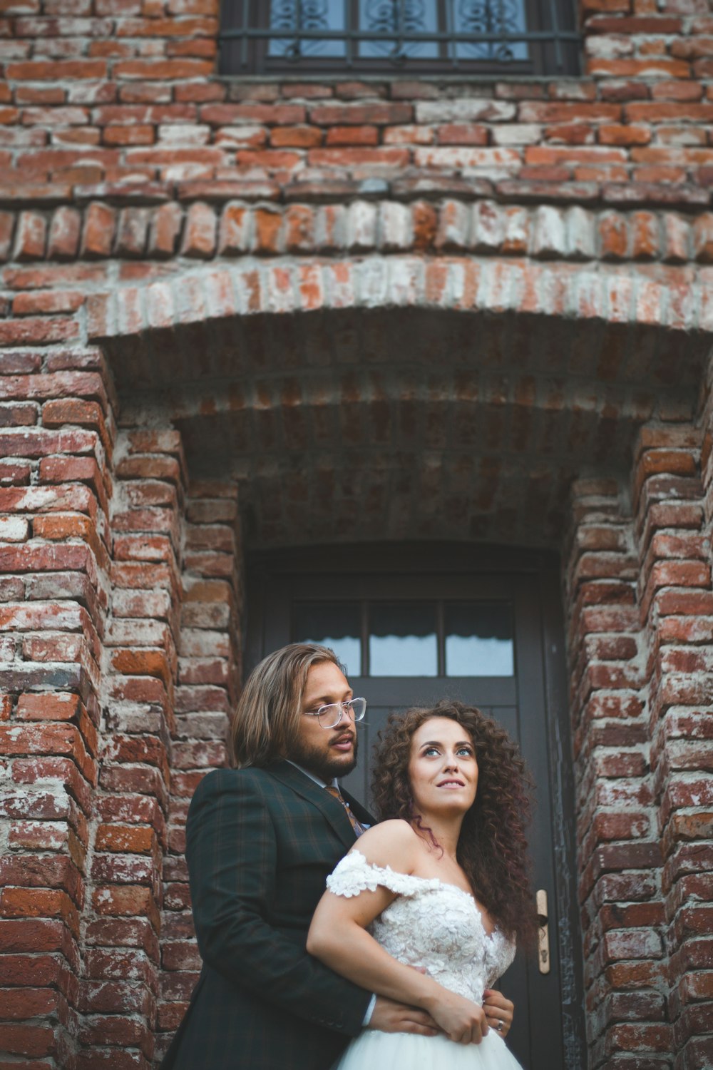 a man and a woman standing in front of a brick building