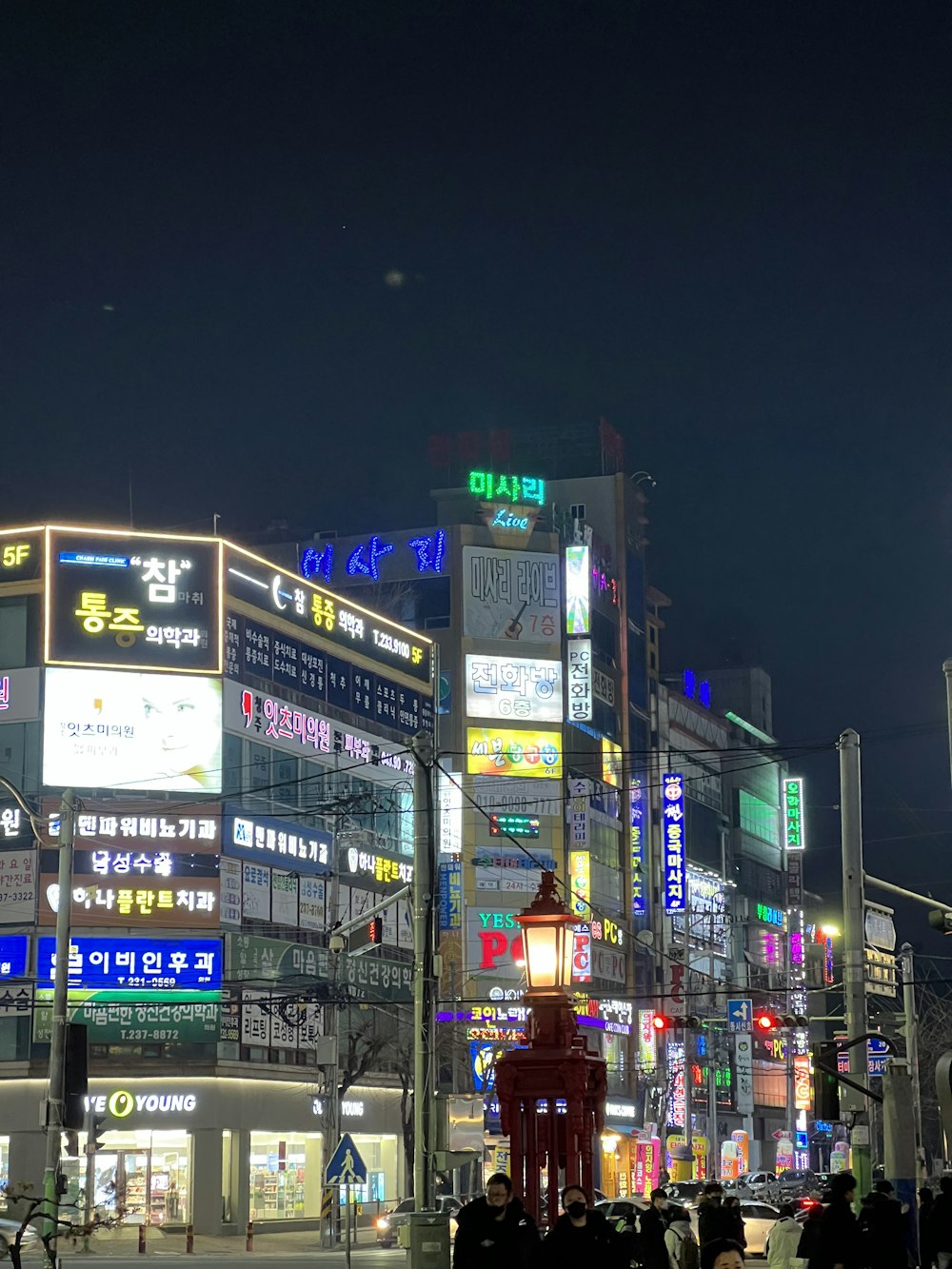 a busy city street at night with a statue in the middle of the street