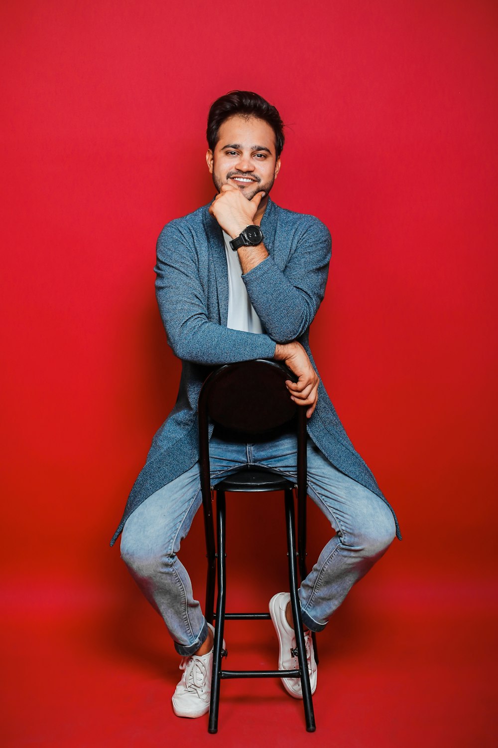 a man sitting on a stool with his hand on his chin