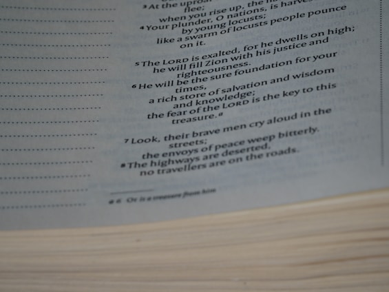 A close-up image of a page from a book reveals text in a poetic or biblical style, detailing themes of justice, righteousness, and desolation in times of trouble. The page edges are visible, and the text is written in a clear, readable font with italics for emphasis.
